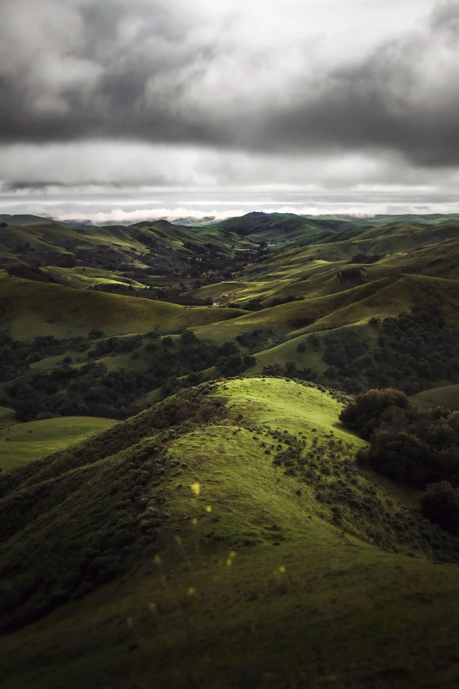 Green rolling hills beneath a dramatic clouded sky